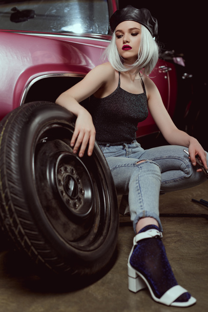 stylish blonde girl in beret changing car wheel - Foto, immagini