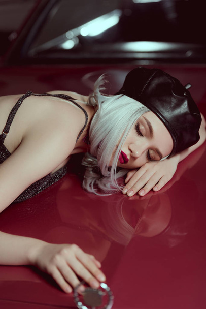 kaunis blondi nainen musta nahka baskeri makaa punainen klassinen auto
   - Valokuva, kuva