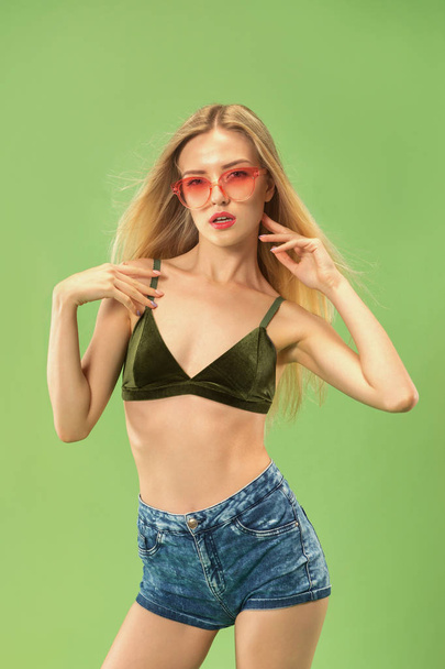 Cute girl in swimsuit posing at studio. Summer portrait caucasian teenager on green background. - 写真・画像