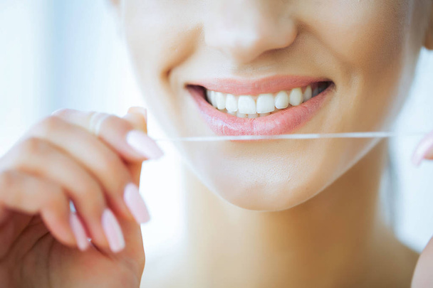 Health and Beauty. Close up. Beautiful Young Girl With White Teeth Cleans Teeth With Dental Floss. A Woman With A Beautiful Smile. Tooth Health - Foto, immagini
