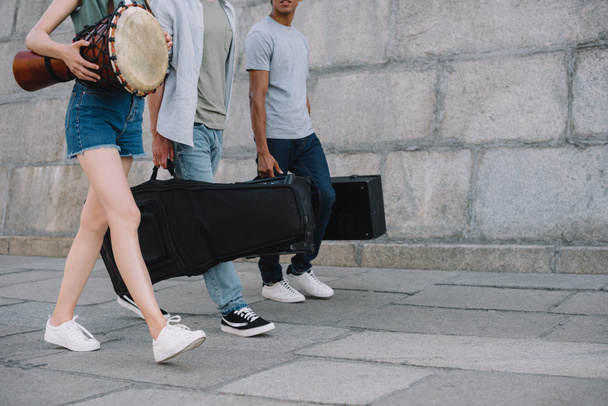 Vista cortada de jovens em banda andando e carregando instrumentos musicais
 - Foto, Imagem