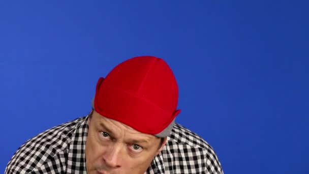 Smiling hispanic handsome guy looking at camera isolated on blue background. Portrait of satisfied man wearing a hat or bandana. - Metraje, vídeo