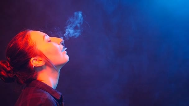 若い女性は、電子タバコを吸います。色の光での喫煙 - 映像、動画