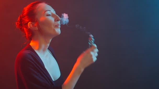 若い女性は、電子タバコを吸います。色の光での喫煙 - 映像、動画