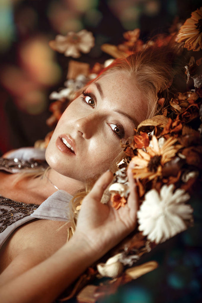 Young beautiful blond woman leaning on flowers - Foto, afbeelding