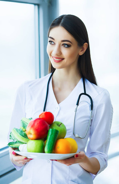Health. Diet and Healthy. Nutrition. Portrait of a Dietitian's Doctor with Fresh Fruits and Vegetables. Beautiful and Young Doctor in the Light Room. High Resolution - Foto, afbeelding
