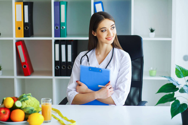 Health. Diet and Healthy. Nutrition. Portrait of a Dietitian's Doctor with Fresh Fruits and Vegetables. Beautiful and Young Doctor in the Light Room. High Resolution - Foto, Imagen