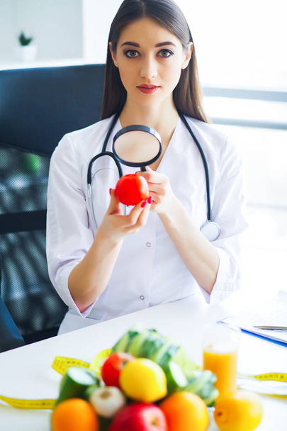 Salud. Dieta y saludable. Doctora dietista sosteniendo tomates frescos en sus manos y sonrisas. Hermoso y joven Doctor. Alta resolución
 - Foto, Imagen