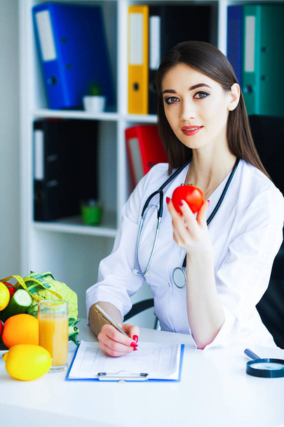 Здоров'я. Дієта і здоровий спосіб життя. Доктор дієтолог тримає свіжі помідори в руках і посмішки. Прекрасний і молодий лікар. Висока роздільна здатність
 - Фото, зображення
