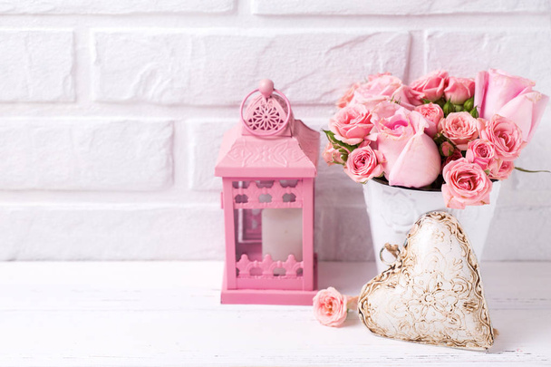 Pink roses flowers  in white pot, decorative heart and pink lantern against  white brick wall. Floral still life.  Selective focus. Copy space. - Foto, immagini