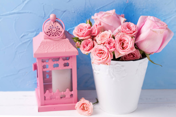 Pink roses flowers  in white pot and pink decorative lantern against  blue wall. Floral still life.  Selective focus.  - Foto, immagini