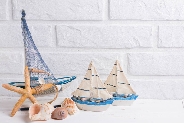 Coastal living  decorations.  Decorative boats, shells and sea stars  near by white brick wall. Selective focus. Place for text. - Φωτογραφία, εικόνα