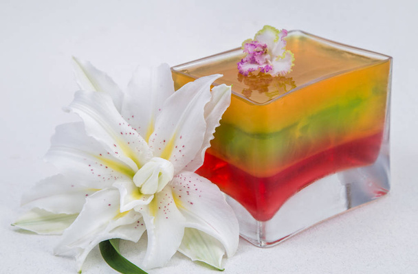 geleia tricolor em um molde de vidro quadrado em um fundo branco
 - Foto, Imagem