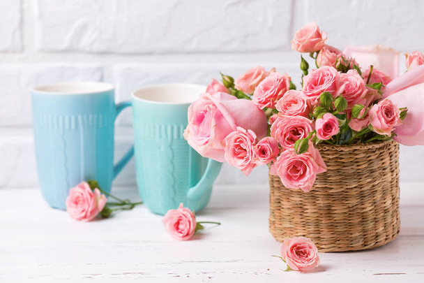 Pink roses flowers and colorful blue cups against  white brick wall. Floral still life.  Selective focus. Place for text. - Φωτογραφία, εικόνα