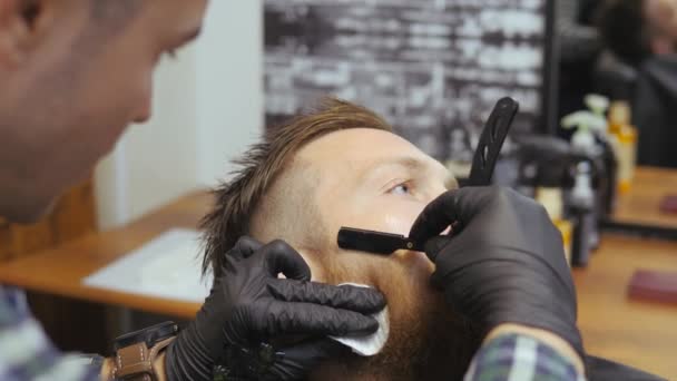 Hairdresser for men. Barbershop. Caring for the beard. Barber with hair clipper works on hairstyle for bearded guy barbershop background. Hipster lifestyle concept. Barber with clipper trimming hair - Footage, Video