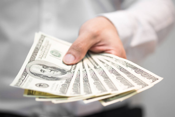 Businessman holding money on hand, Spreading one hundred US Dollar bills in financial concepts, Selective focus. - Φωτογραφία, εικόνα
