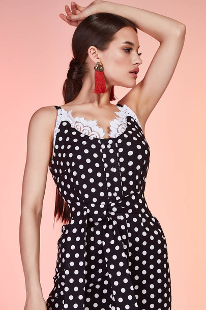 Beautiful sexy woman pretty face long brunette hair wear black polka dot skinny dress fashion style clothes for business woman office casual walk summer collection jewelry earrings glamour model pose. - Foto, afbeelding