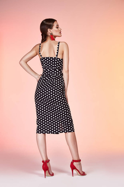 Beautiful sexy woman pretty face long brunette hair wear black polka dot skinny dress fashion style clothes for business woman office casual walk summer collection jewelry earrings glamour model pose. - Photo, image