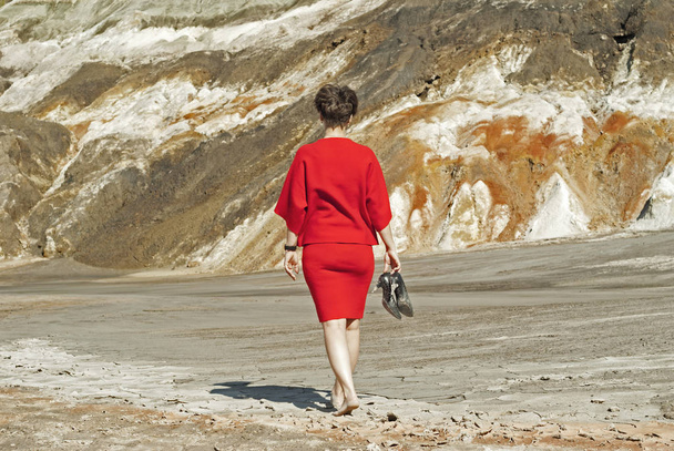 Kobieta w sukience biznes czerwony, zdejmując buty, chodzenie boso na opuszczony Kanion z ją z powrotem do Viewer - Zdjęcie, obraz