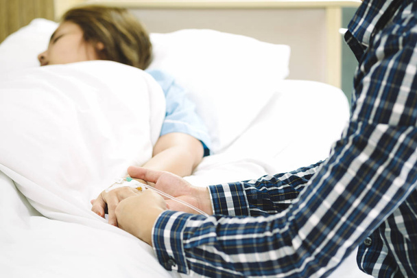 Man hand holding woman patient hand receiving saline solution by intravenous injection on bed in hospital for reassuring and encouragement wife. Medical treatment, healthcare, family and love concept. - Φωτογραφία, εικόνα