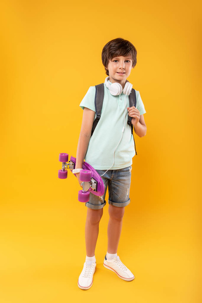 Exuberant boy holding his skateboard - Foto, Imagen