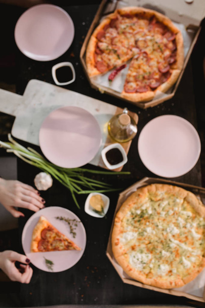 Pizza set on wooden table with bright plates for party. Dark rustic toning food photo. Top view image. - Fotó, kép
