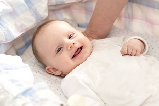Beşiğinde yatan sevimli gülümseyen bebek kız portresi - Fotoğraf, Görsel