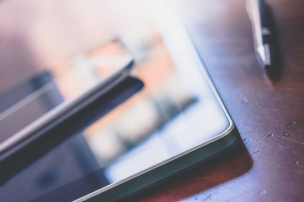 Smartphone de negócios e tablet com reflexão ao lado de um Biro na tabela de madeira
 - Foto, Imagem