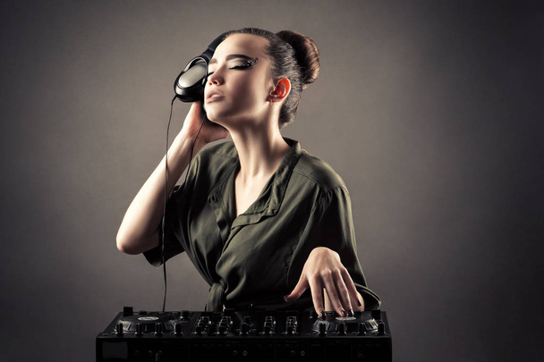 charming girl behind DJ remotes in headphones  - Photo, Image