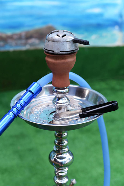 beautiful national calabash shisha bulb of blue color with a hose on the table on the background of a palm tree - Photo, Image