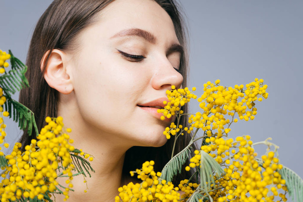 charming young girl enjoying the scent of yellow mimosa - Fotoğraf, Görsel