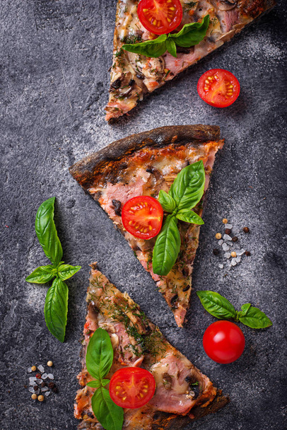 Pezzi di pizza nera con pomodori e basilico
 - Foto, immagini