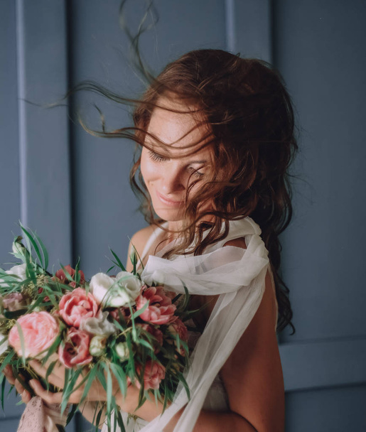 young beautiful girl and bouquet of flowers on the background of a textured wall - Foto, Imagem