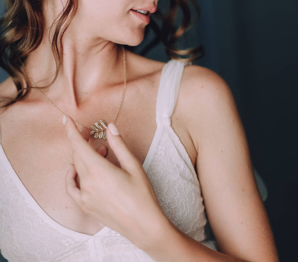 girl in a white dress adjusts an accessory around her neck - Φωτογραφία, εικόνα
