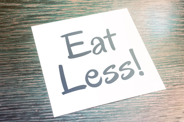 Їжте менше нагадування на папері лежачи на дерев'яному столі
 - Фото, зображення