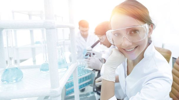 Investigator checking test tubes, Woman wears protective goggles - Foto, Imagen