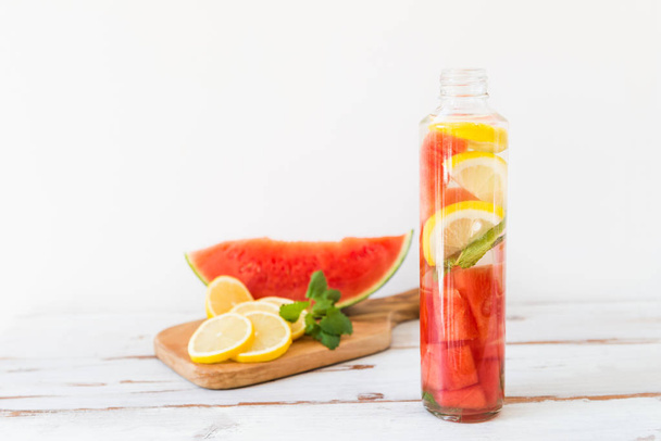 Detox Infused Water with Lemon, Watermelon and Mint in Sports Bottle, with cut pieces of lemon and watermelon nearby - Photo, Image