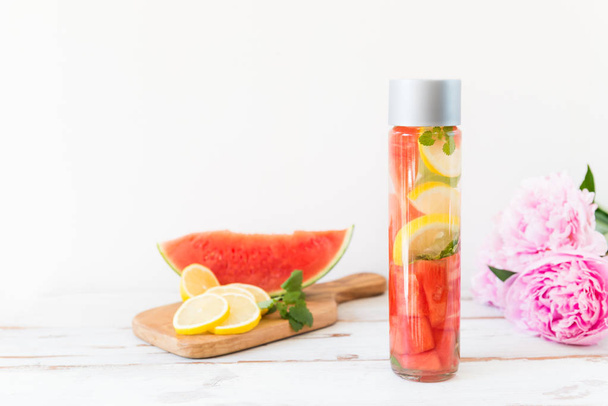 Detox Infused Water with Lemon, Watermelon and Mint in Sports Bottle, with cut pieces of lemon and watermelon nearby - Photo, Image