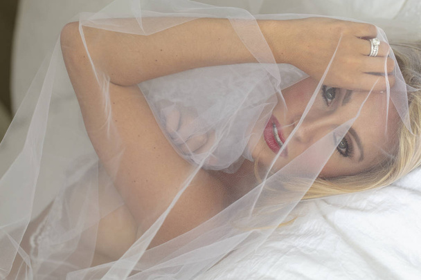 A beautiful blonde lingerie model relaxing at home before her wedding day - Фото, изображение