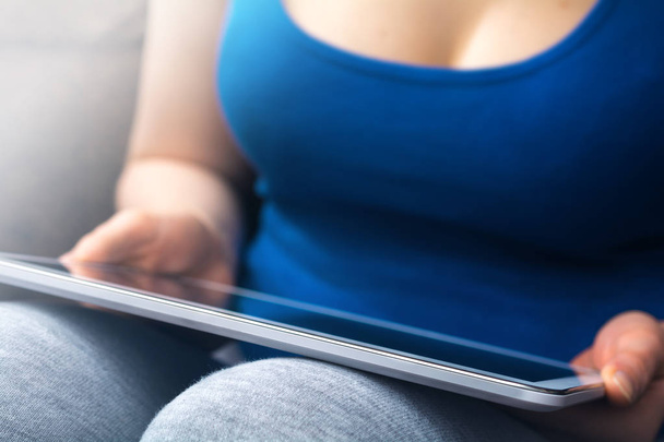 Rondborstige vrouw In Tank Top een Tablet leunend op haar knieën - Foto, afbeelding