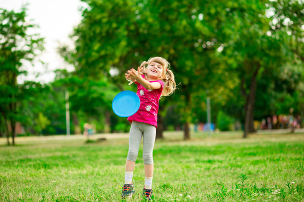 Little girl play with flying disk in motion, playing leisure activity games in summer park - Foto, Imagen