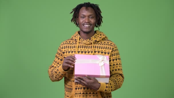 Young handsome African man opening gift box and looking surprised - Footage, Video