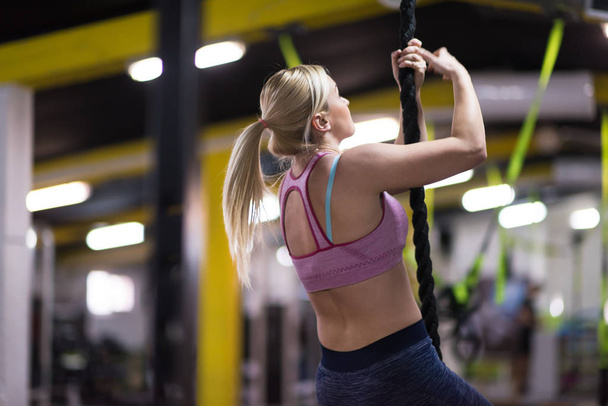 young muscular woman doing rope climbing in cross fitness gym - Fotoğraf, Görsel