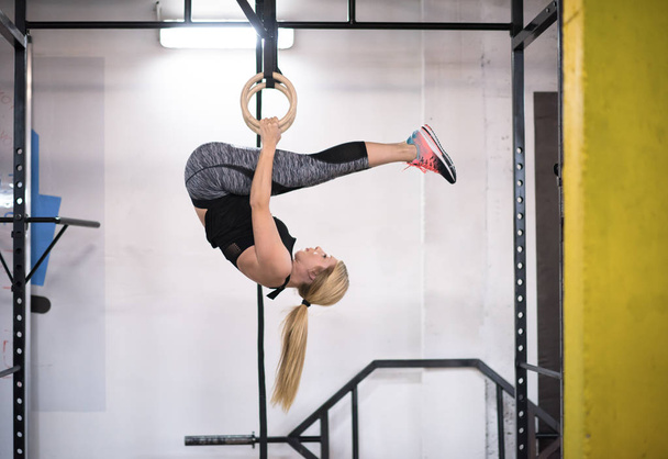 young athletic woman working out on gymnastic rings at the cross fitness gym - Foto, afbeelding