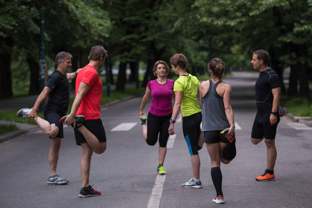 healthy runners team warming up and stretching in city park before morning training - 写真・画像