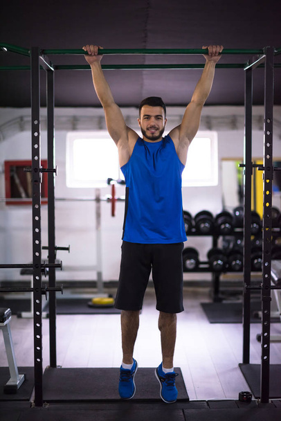 young muscular man doing pull ups on the horizontal bar as part of Cross fitness Training - Foto, immagini