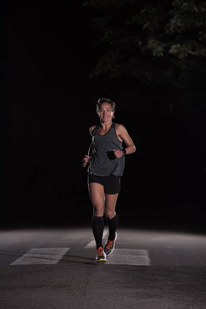 筋肉女性ランナーの自然の美しい道で夜マラソンのトレーニングに合わせて. - 写真・画像