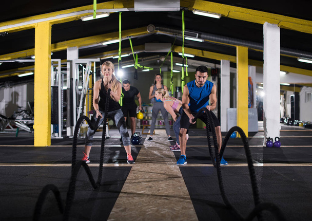 young fit sports couple working out in functional training gym doing  battle ropes cross fitness exercise - Fotoğraf, Görsel