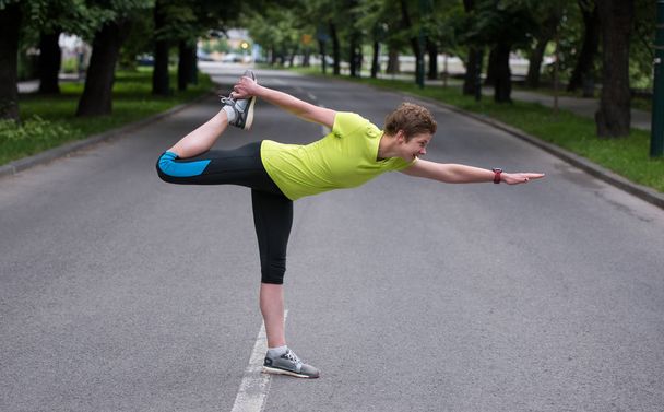 healthy female runner warming up and stretching in city park before morning training - Фото, зображення