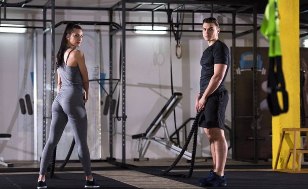 young fit sports couple working out in functional training gym doing  battle ropes cross fitness exercise - Valokuva, kuva